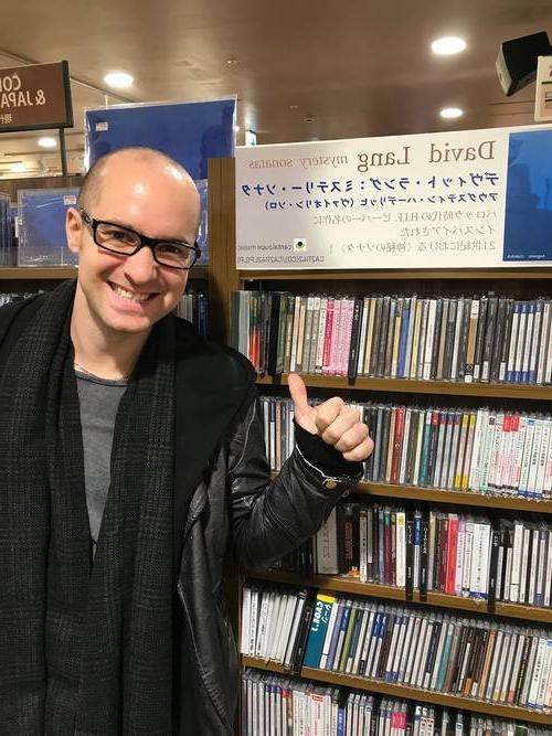 Adam Cuthbert posing in front of CDs in a store